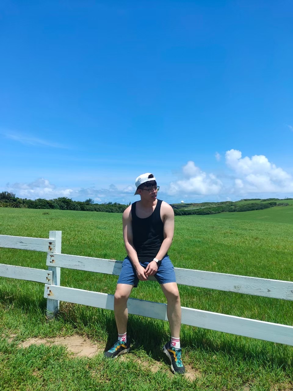 阿穎旅行時坐在遼闊草原前的白色圍欄上